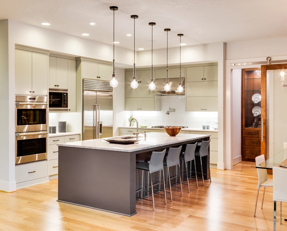Bright modern kitchen remodel with white cabinets, stainless steel appliances, and large windows. Updated kitchen design featuring clean countertops and a spacious layout.
