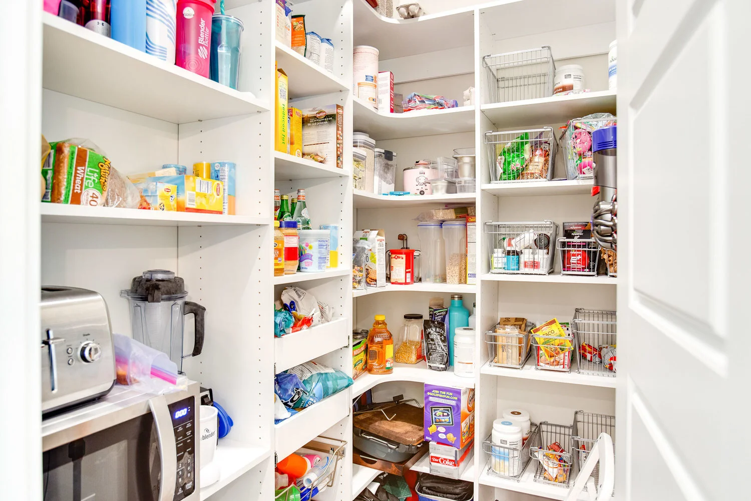 Walk-in pantry with custom shelving, storage baskets, and organized food containers. Kitchen storage solution designed to maximize pantry space and organization.